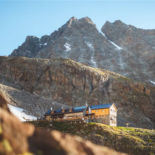 Ein charmantes Berghaus, umgeben von majestätischen Bergen. Die Landschaft ist klar und einladend.