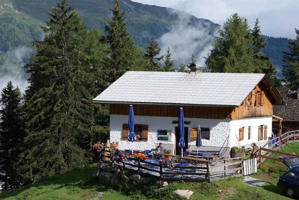 Ein gemütliches Haus in den Bergen, umgeben von hohen Tannen. Der Garten ist hübsch angelegt und lädt zum Entspannen ein.