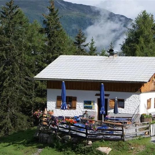 Ein gemütliches Haus in den Bergen, umgeben von hohen Tannen. Der Garten ist hübsch angelegt und lädt zum Entspannen ein.
