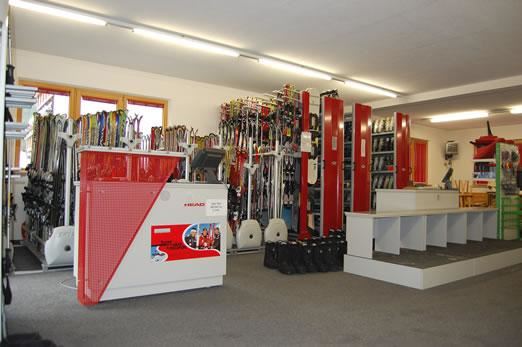 Ein Geschäft für Skiausrüstung mit vielen Skiern und Zubehör. Der Verkaufsbereich ist hell und ordentlich gestaltet.