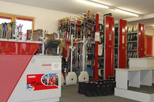 Ein Geschäft für Skiausrüstung mit vielen Skiern und Zubehör. Der Verkaufsbereich ist hell und ordentlich gestaltet.