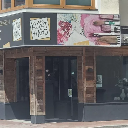 Ein modernes Geschäft mit Holzelementen und großen Fenstern. Die Fassade ist mit bunten Grafiken und einer einladenden Beschilderung gestaltet.