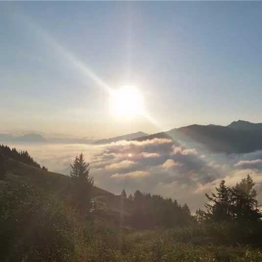 A beautiful sunrise over the mountains, with fog covering the valley. The sun shines brightly and creates a peaceful atmosphere.