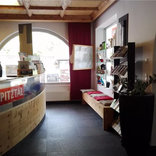 A modern reception area with a curved counter and a friendly atmosphere. In the background, cozy seating and a large window front can be seen.