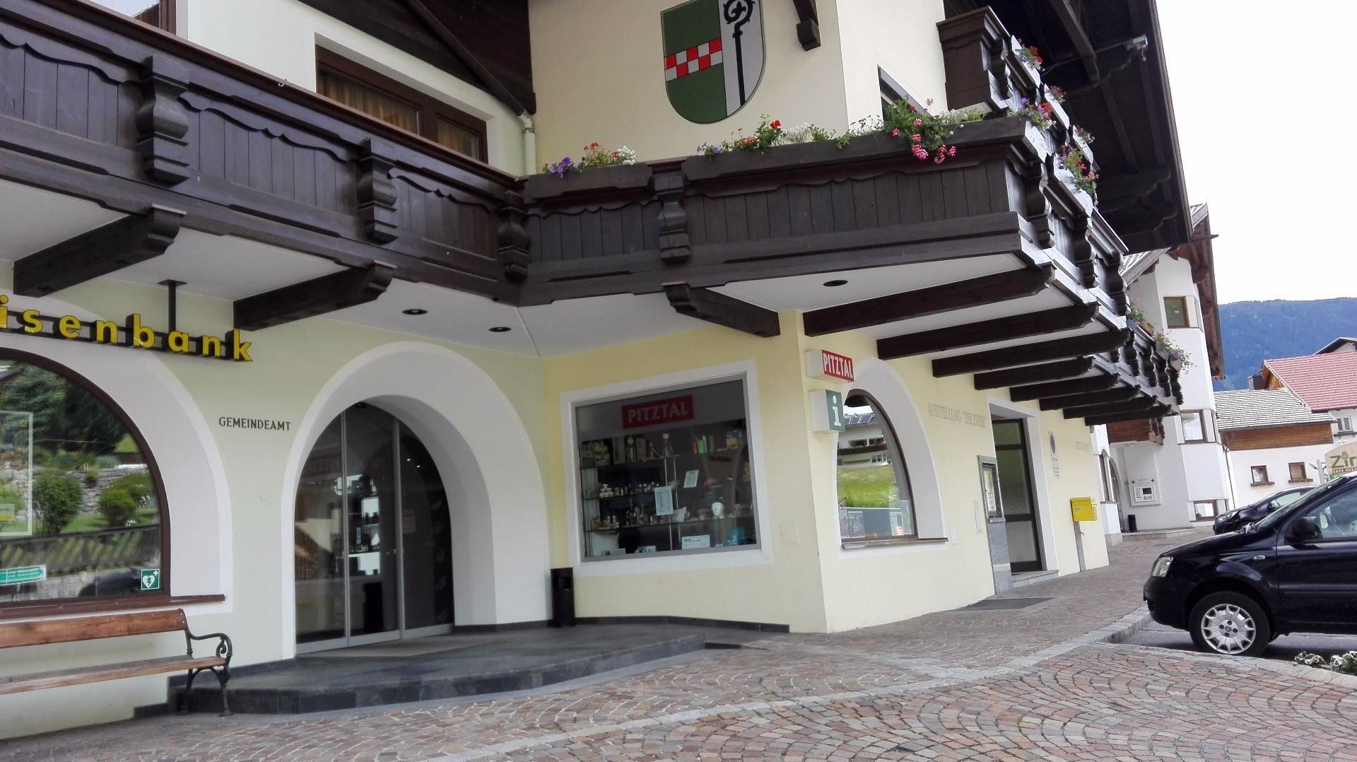 A cozy street with a building that has a traditional style. The facade is in light colors and features wooden elements.