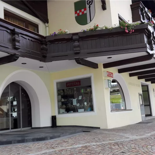 A cozy street with a building that has a traditional style. The facade is in light colors and features wooden elements.