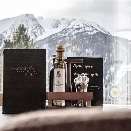 An elegant table with drinks and menus in front of an impressive mountain landscape. The view showcases snow-covered peaks under a clear sky.