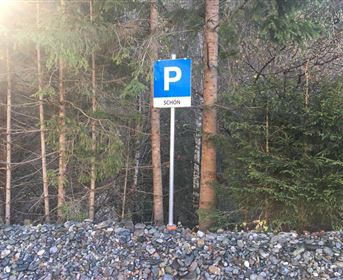 A parking sign stands between trees. The inscription on the sign says "BEAUTIFUL".