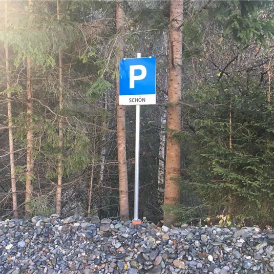 A parking sign stands between trees. The inscription on the sign says "BEAUTIFUL".