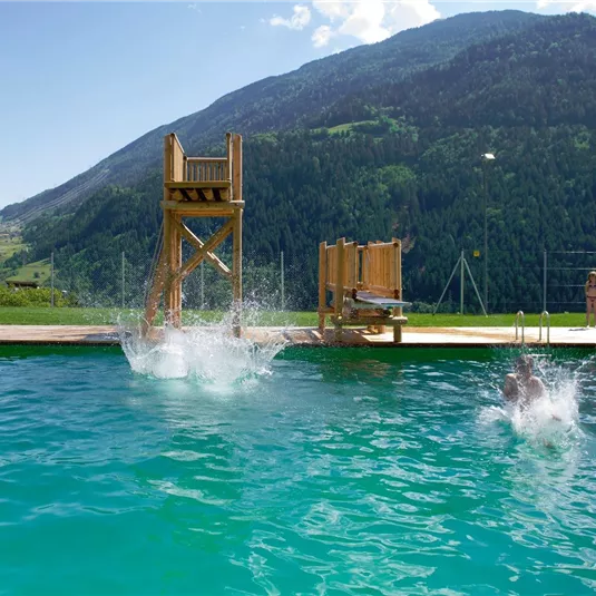 Ein herrlicher Schwimmingpool mit einem Sprungturm. Kinder und Erwachsene genießen einen sonnigen Tag im Freien.
