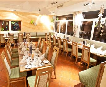 A stylish restaurant with long tables, elegantly set for a celebration. Large windows provide plenty of light and an inviting atmosphere.
