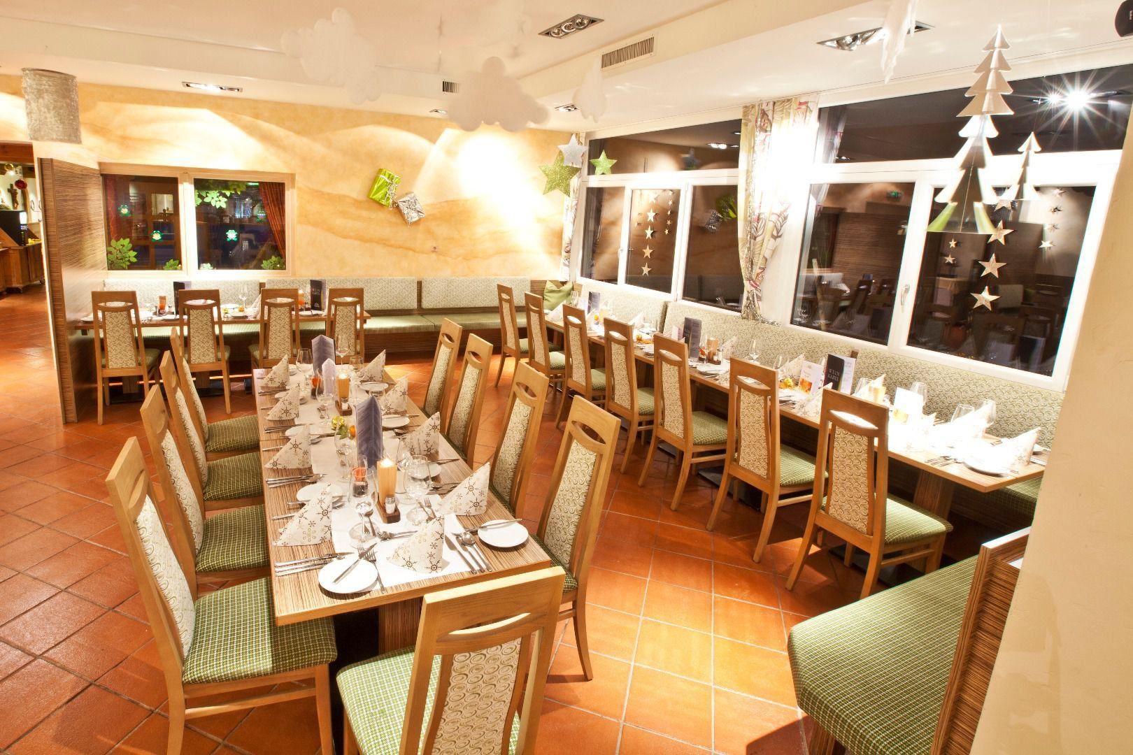 A stylish restaurant with long tables, elegantly set for a celebration. Large windows provide plenty of light and an inviting atmosphere.