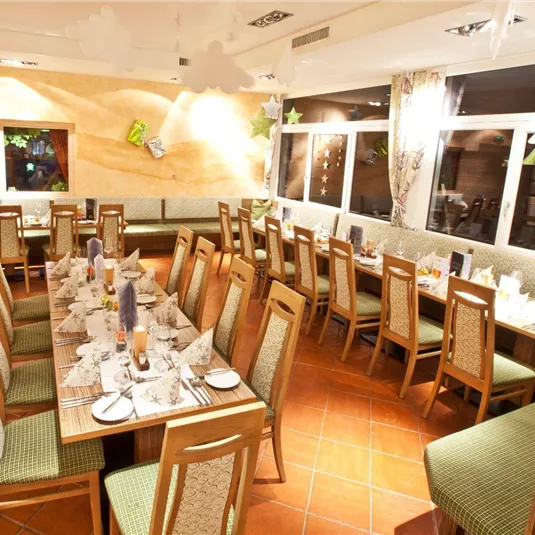 A stylish restaurant with long tables, elegantly set for a celebration. Large windows provide plenty of light and an inviting atmosphere.