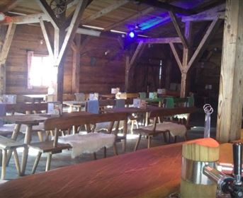 Ein rustikales Restaurant mit Holzdekor und langen Tischen. Der Bereich ist hell erleuchtet und schafft eine gemütliche Atmosphäre.