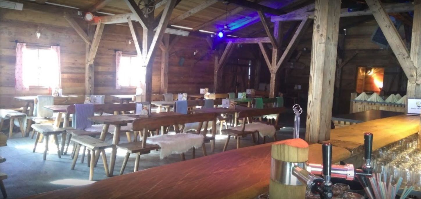 Ein rustikales Restaurant mit Holzdekor und langen Tischen. Der Bereich ist hell erleuchtet und schafft eine gemütliche Atmosphäre.