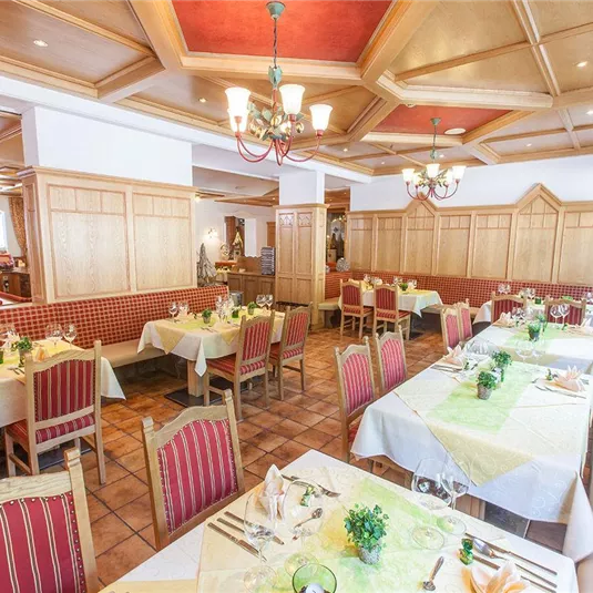 Ein einladendes Restaurant mit elegant gedeckten Tischen und gemütlicher Holzausstattung. Die Atmosphäre ist freundlich und einladend.