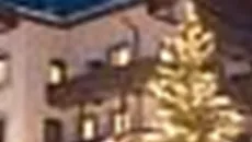 A picturesque hotel in the mountains, surrounded by snow. A lit Christmas tree creates a festive atmosphere.