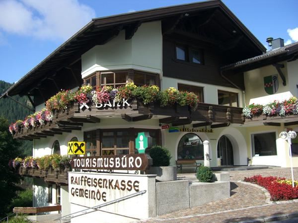 Ein traditionelles Gebäude mit einem Tourismusbüro und blühenden Pflanzen. Die Fassade ist schön und einladend gestaltet.