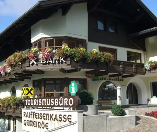 Ein traditionelles Gebäude mit einem Tourismusbüro und blühenden Pflanzen. Die Fassade ist schön und einladend gestaltet.