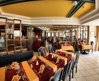 A cozy restaurant with elegant tables and a yellow accent. The atmosphere is inviting and ideal for a meal with friends or family.