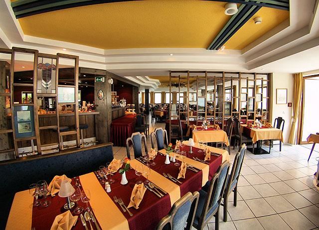 Ein gemütliches Restaurant mit eleganten Tischen und gelbem Akzent. Die Atmosphäre ist einladend und ideal für ein Essen mit Freunden oder Familie.