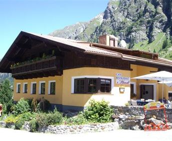 Ein traditionelles Alpenhaus mit einem gemütlichen Restaurant. Umgeben von grüner Natur und majestätischen Bergen.