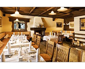 Ein gemütliches Restaurant mit Holzdekor und einem Kamin. Die Tische sind schön gedeckt und es gibt eine einladende Atmosphäre.