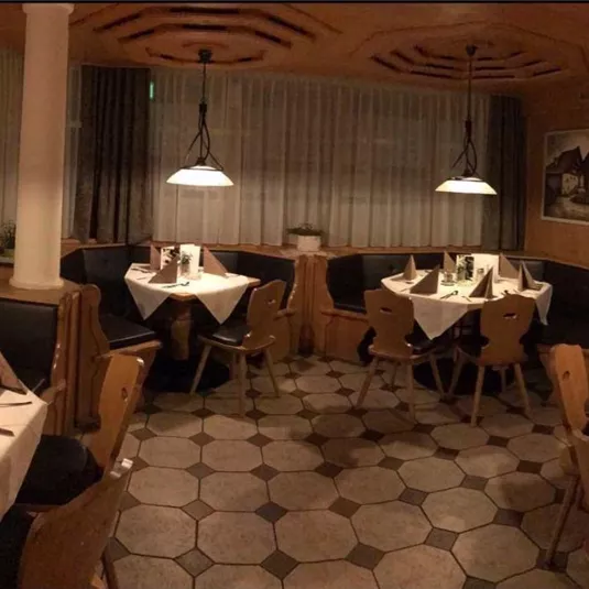 A cozy restaurant with tables set for guests. The warm wood decor and soft lighting create an inviting atmosphere.