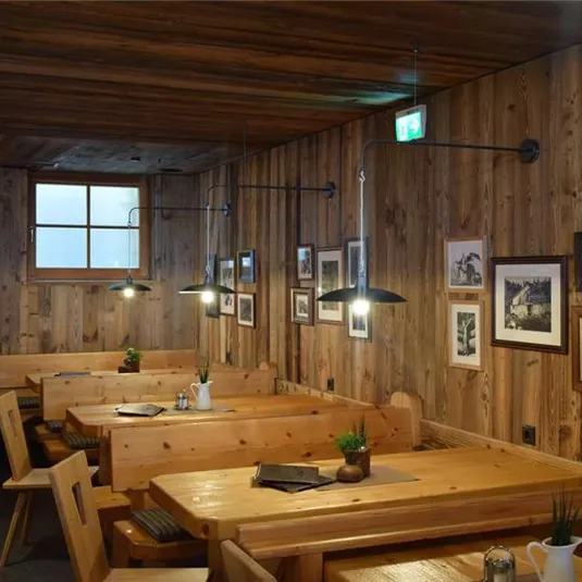 Ein rustikales Restaurant mit Holzwänden und gemütlichen Sitzplätzen. Die Wände sind mit Bildern dekoriert, und dezente Beleuchtung sorgt für eine angenehme Atmosphäre.