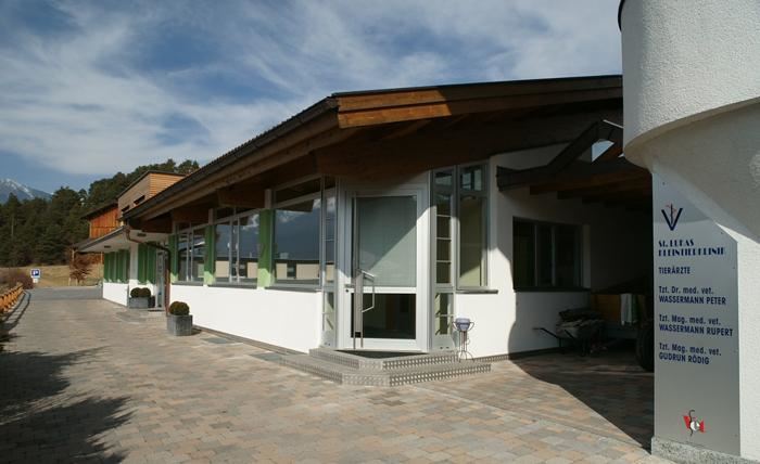 A modern building with a lot of glass and wood. The surroundings are mountainous and the sky is clear.