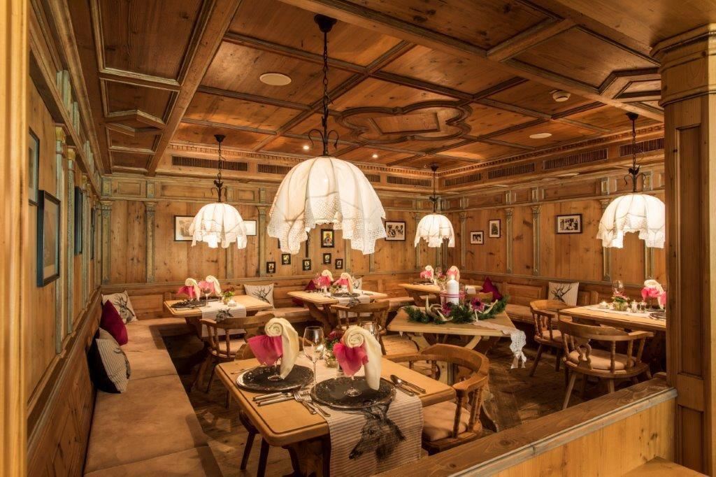 Ein gemütliches Restaurant mit Holzdekor und sanfter Beleuchtung. Tische sind schick gedeckt mit Blumen und eleganten Tischdecken.