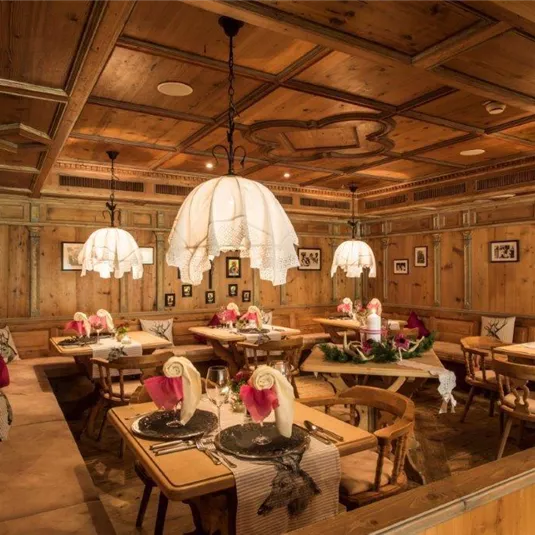 Ein gemütliches Restaurant mit Holzdekor und sanfter Beleuchtung. Tische sind schick gedeckt mit Blumen und eleganten Tischdecken.