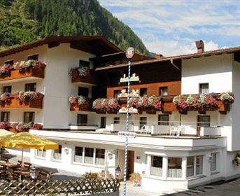 Ein gemütliches Hotel mit Balkon und blühenden Pflanzen. Es befindet sich in einer malerischen Berglandschaft.