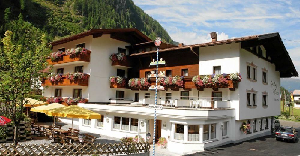 Ein gemütliches Hotel mit Balkon und blühenden Pflanzen. Es befindet sich in einer malerischen Berglandschaft.