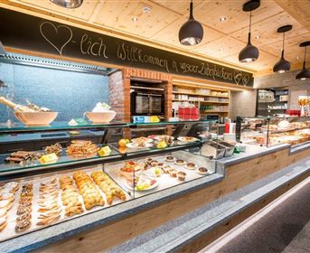Ein einladender Backshop mit einer großen Auswahl an frischen Backwaren. Die Theke ist liebevoll dekoriert und bietet süße und herzhafte Leckereien.