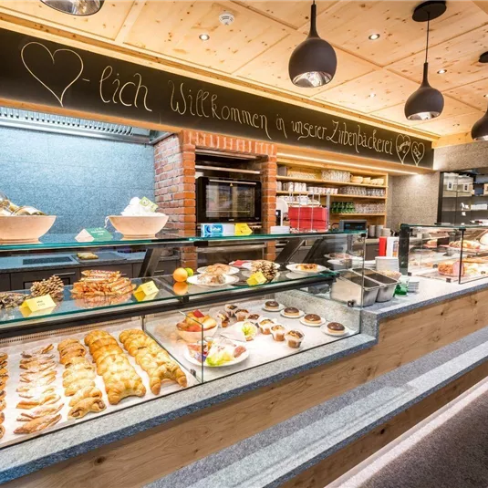 Ein einladender Backshop mit einer großen Auswahl an frischen Backwaren. Die Theke ist liebevoll dekoriert und bietet süße und herzhafte Leckereien.