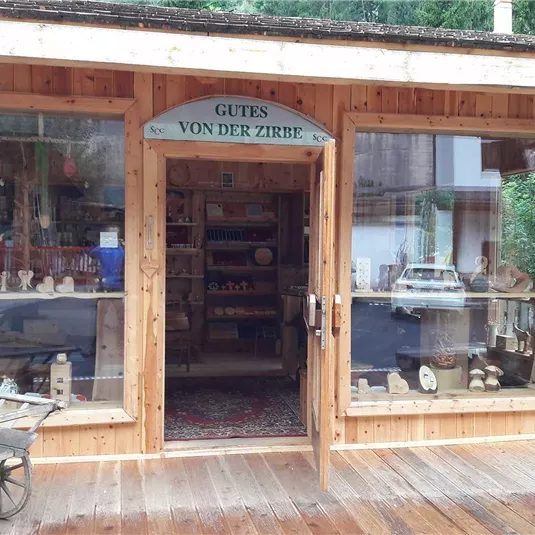 Ein Holzladen mit einem einladenden Eingang und großen Fenstern. Im Inneren sind verschiedene handgefertigte Kunstwerke und Souvenirs zu sehen.
