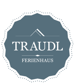 A stylish logo for the holiday home "Traudl". It features an elegant design with a modern lettering on a blue background.