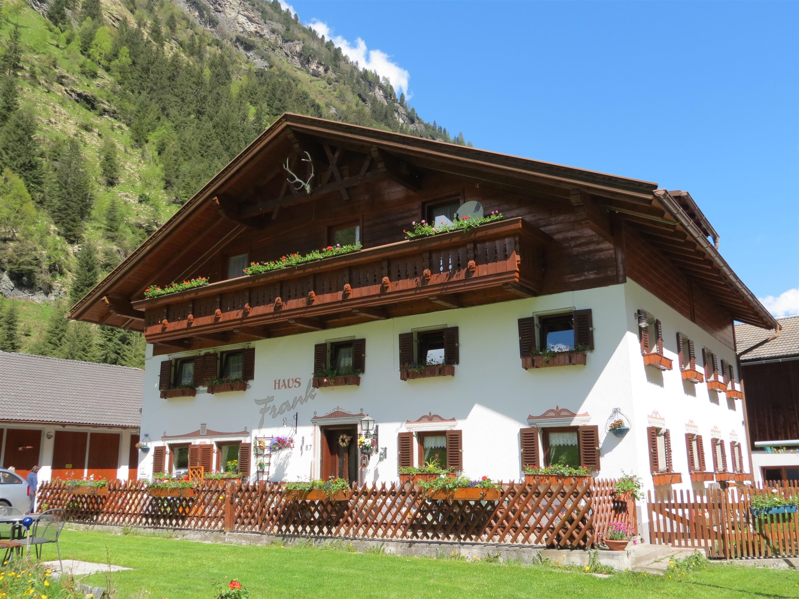 A charming, traditional chalet in the mountains. It has several windows, balconies, and a well-maintained garden.
