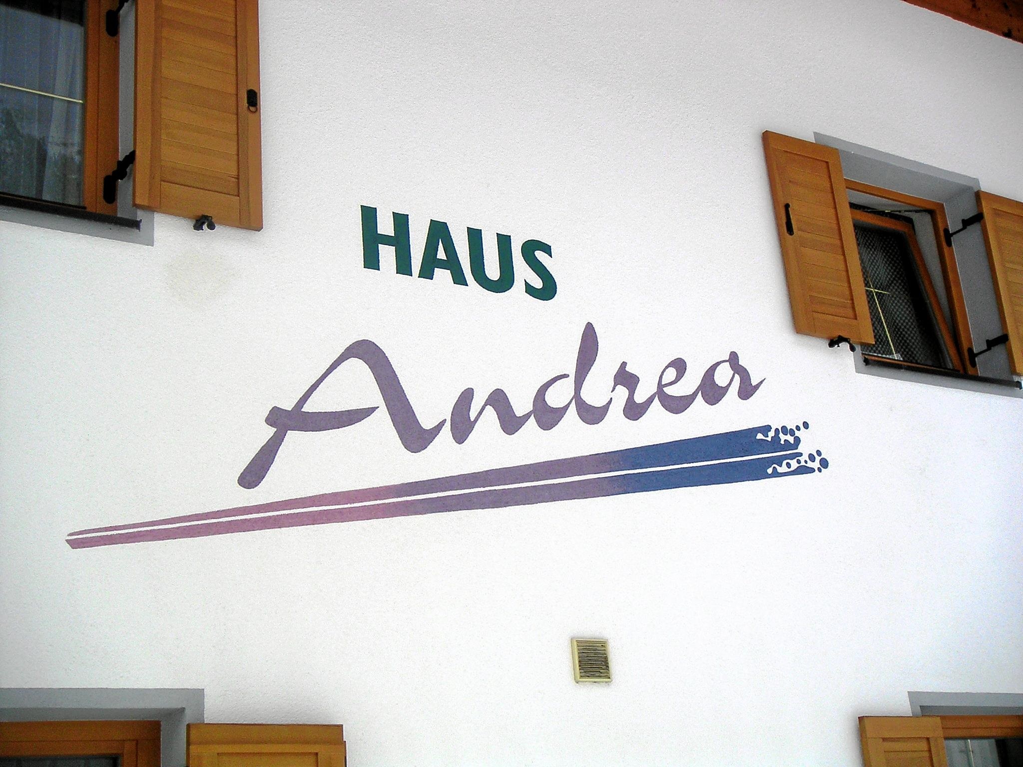 A building with the inscription "HAUS Andrea" on the wall. The windows are equipped with wooden shutters.