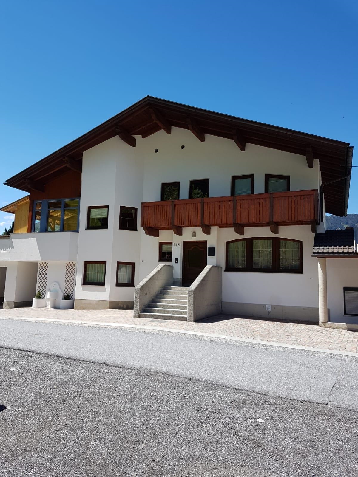 A modern house in the Alps with a spacious balcony. The sky is clear and blue.