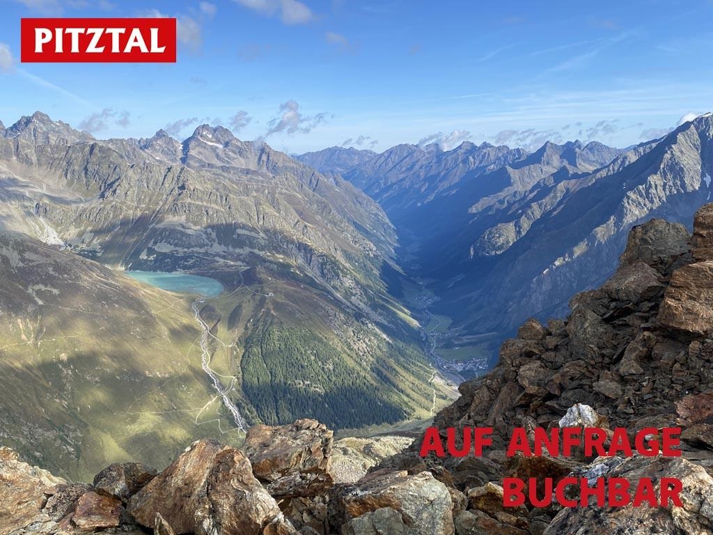 An impressive mountain landscape in the Pitztal with majestic mountains and a clear sky. In the foreground, rocky cliffs can be seen.