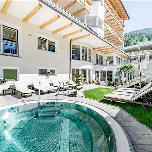 Ein luxuriöser Außenbereich mit einem Whirlpool und Liegen. Die Umgebung ist von gepflegtem Grün und modernem Design umgeben.