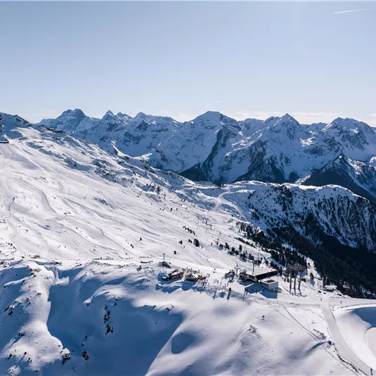 Eine beeindruckende Winterlandschaft mit schneebedeckten Bergen und klarem Himmel. Die Berggipfel erheben sich majestätisch über die Umgebung.