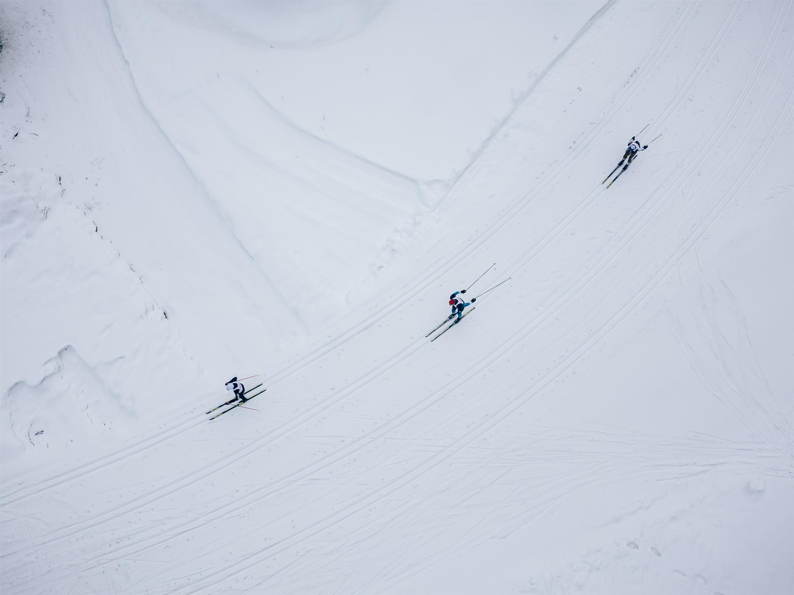 Eine winterliche Landschaft mit schneebedeckten Bergen und einem klaren blauen Himmel. Im Vordergrund führt ein verschneiter Weg durch die idyllische Umgebung.