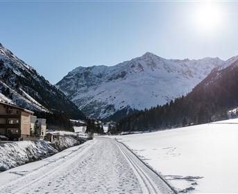 Ein malerisches Schneeapsühls von Bergen und einem klaren Himmel. Der Weg führt durch eine wunderschöne Winterlandschaft.