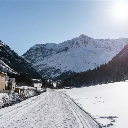 Ein malerisches Schneeapsühls von Bergen und einem klaren Himmel. Der Weg führt durch eine wunderschöne Winterlandschaft.