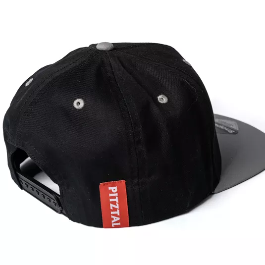 A black cap with a gray shimmering visor. On the side is a red label with the inscription "Pitztal".