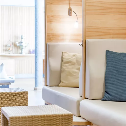 Eine moderne Lounge mit hellen Holzoberflächen und bequemen Sofas. Auf dem Tisch stehen stilvolle Korbgestelle, die eine entspannte Atmosphäre schaffen.