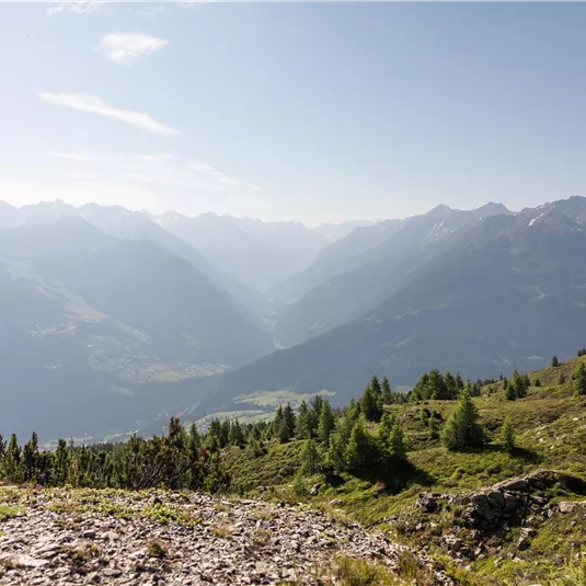 An impressive mountain landscape with gentle hills and a clear sky. In the background, the majestic mountains can be seen.